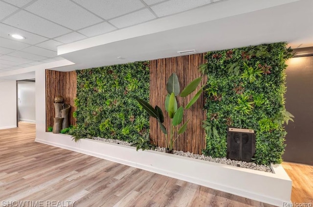 interior space featuring a drop ceiling, visible vents, baseboards, and wood finished floors