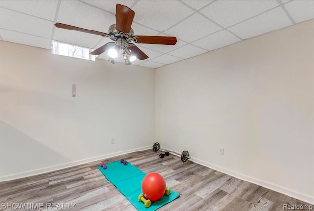 workout room with a drop ceiling, baseboards, and wood finished floors