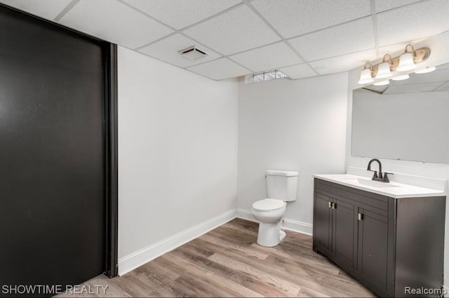 bathroom featuring toilet, a paneled ceiling, wood finished floors, and visible vents