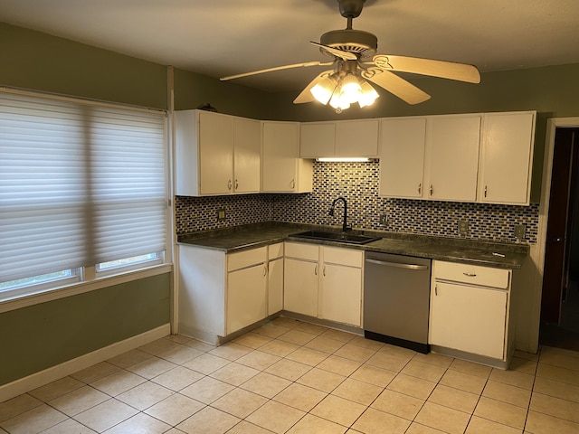 kitchen with dark countertops, white cabinetry, dishwasher, and a sink