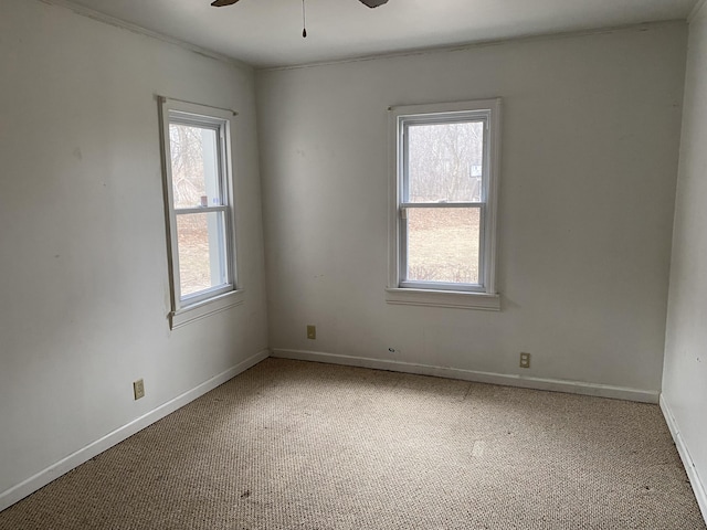 carpeted empty room with a healthy amount of sunlight, ceiling fan, and baseboards