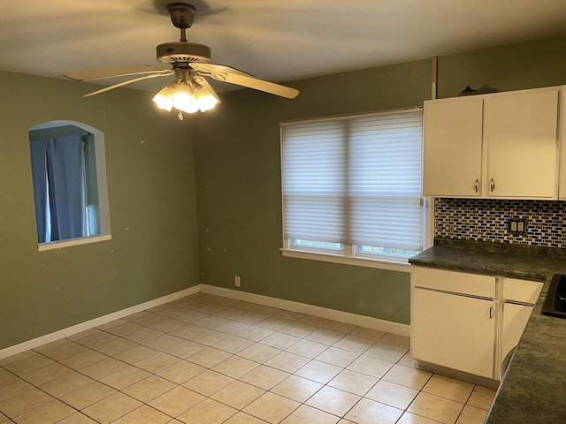 interior space featuring light tile patterned flooring, white cabinetry, baseboards, tasteful backsplash, and dark countertops