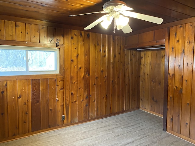 spare room featuring wood walls, ceiling fan, and wood finished floors