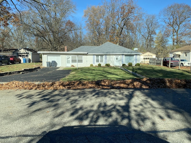 view of front facade with a front lawn, an attached garage, fence, and aphalt driveway