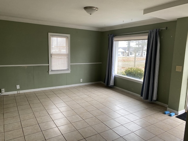 unfurnished room featuring a wainscoted wall, baseboards, and tile patterned floors