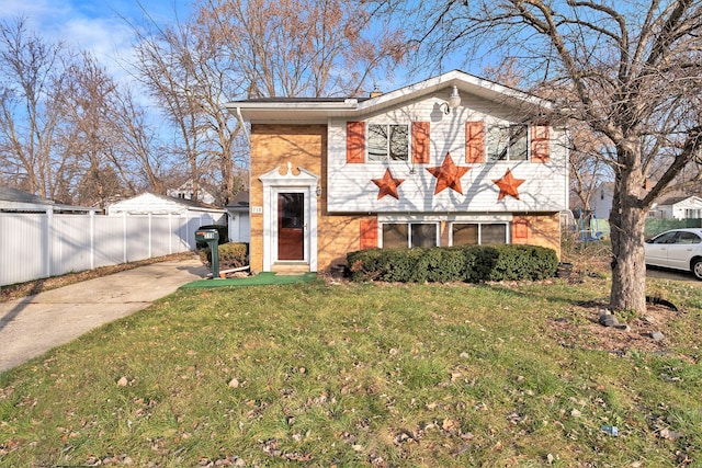 view of front facade featuring concrete driveway, brick siding, fence, and a front lawn