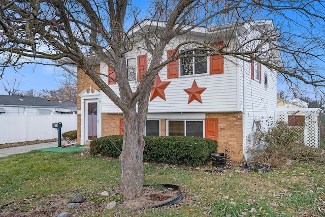 view of front of property with a front yard, brick siding, and fence