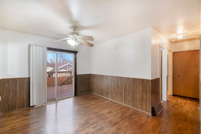 unfurnished room featuring a wainscoted wall, wooden walls, visible vents, and wood finished floors