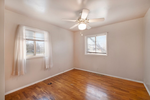 spare room featuring ceiling fan, wood finished floors, visible vents, and baseboards