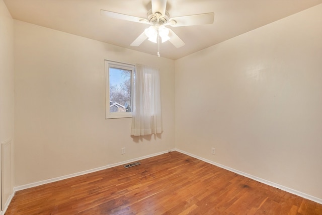 empty room featuring a ceiling fan, visible vents, baseboards, and wood finished floors