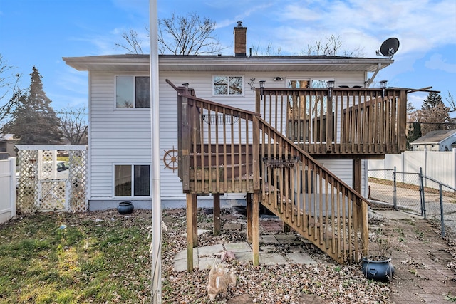 rear view of property with a chimney, stairway, a gate, fence, and a deck