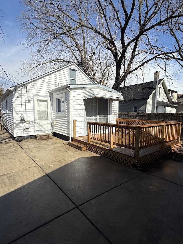 rear view of property featuring fence, a deck, and a patio