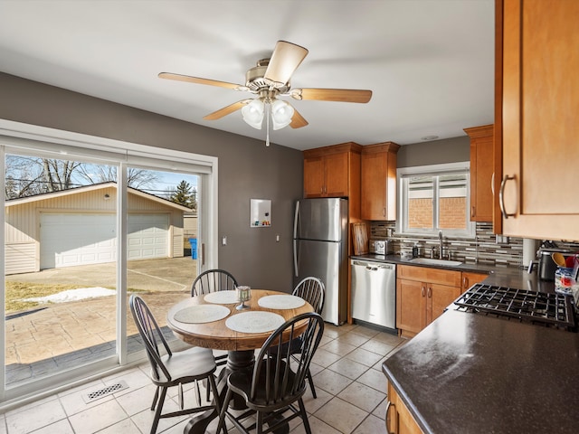 kitchen featuring appliances with stainless steel finishes, dark countertops, a sink, and tasteful backsplash