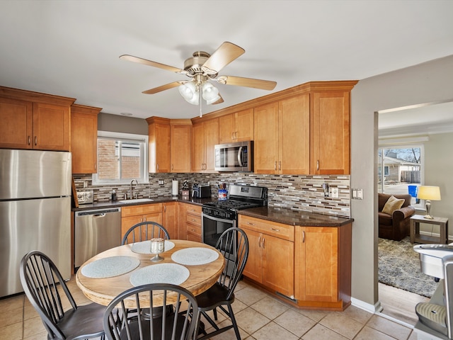 kitchen featuring dark countertops, appliances with stainless steel finishes, backsplash, and a sink