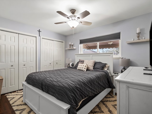 bedroom featuring ceiling fan, wood finished floors, and two closets