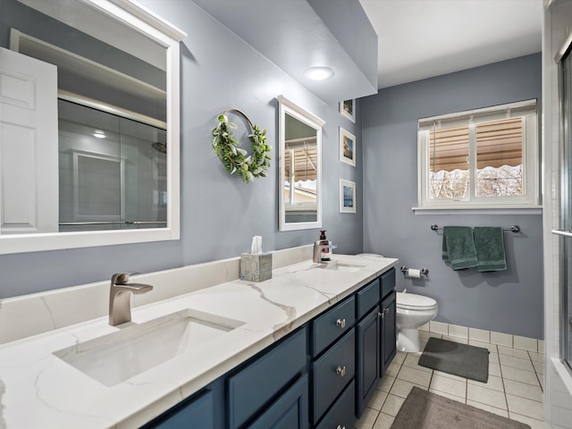 bathroom with double vanity, a stall shower, a sink, and toilet