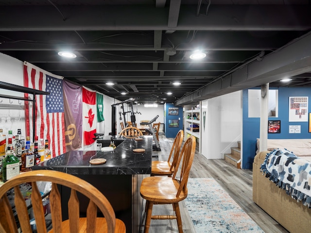 bar with indoor wet bar, stairway, and wood finished floors