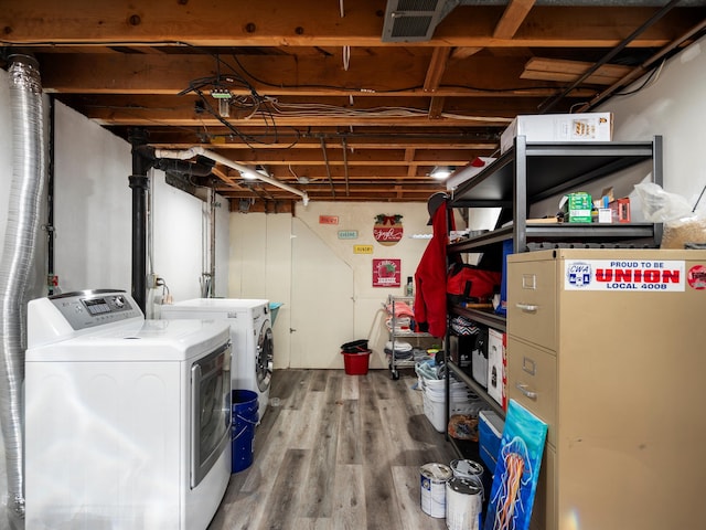 unfinished basement with washing machine and dryer, visible vents, and wood finished floors