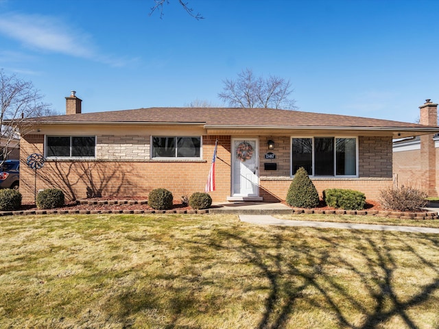 ranch-style home featuring a front yard, brick siding, a chimney, and roof with shingles