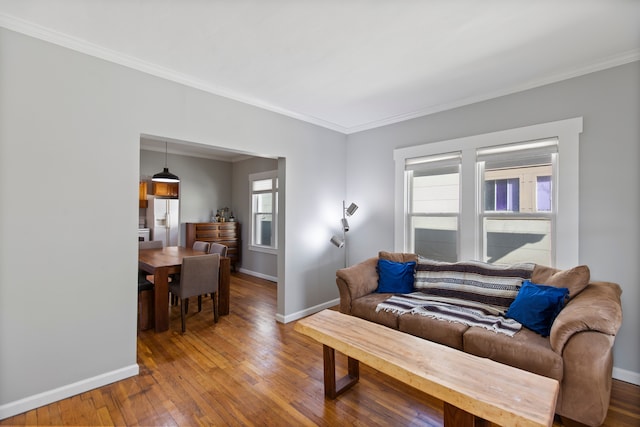 living room featuring wood-type flooring, baseboards, and ornamental molding