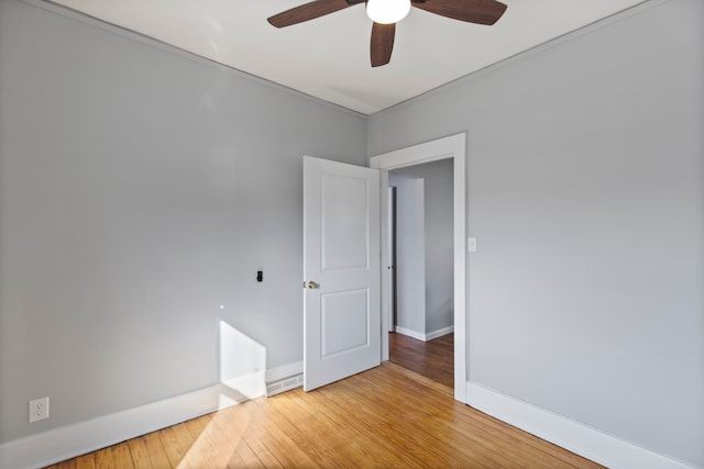 empty room featuring a ceiling fan, light wood-type flooring, and baseboards