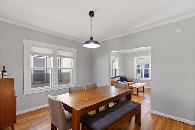 dining space with crown molding, light wood-type flooring, plenty of natural light, and baseboards