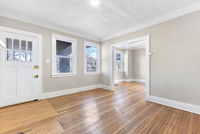 foyer featuring light wood-style floors, baseboards, ornamental molding, and a textured ceiling