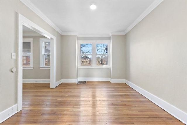 spare room featuring light wood-style flooring, visible vents, baseboards, and crown molding