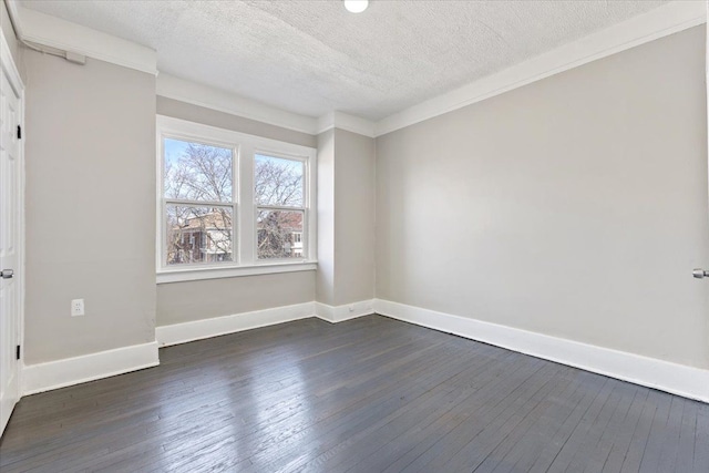 empty room with dark wood-style floors, ornamental molding, and baseboards