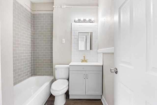 bathroom with bathing tub / shower combination, toilet, wood finished floors, vanity, and backsplash