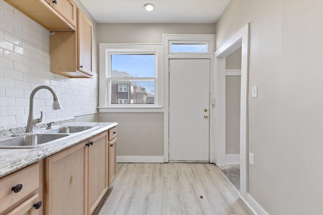 kitchen featuring tasteful backsplash, light countertops, a sink, and light brown cabinetry