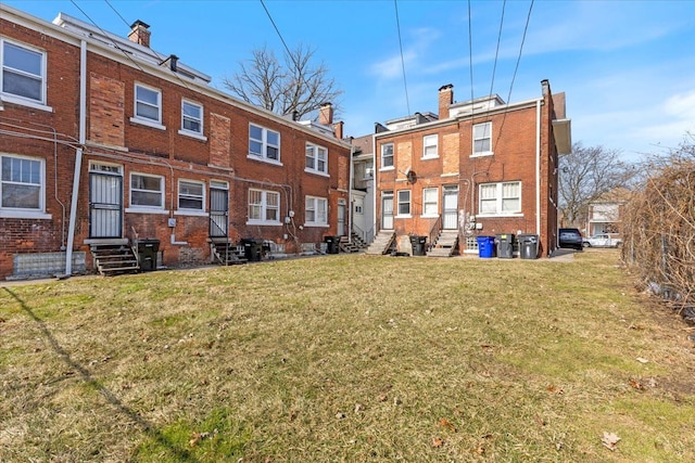 rear view of house with entry steps, a yard, brick siding, and a residential view