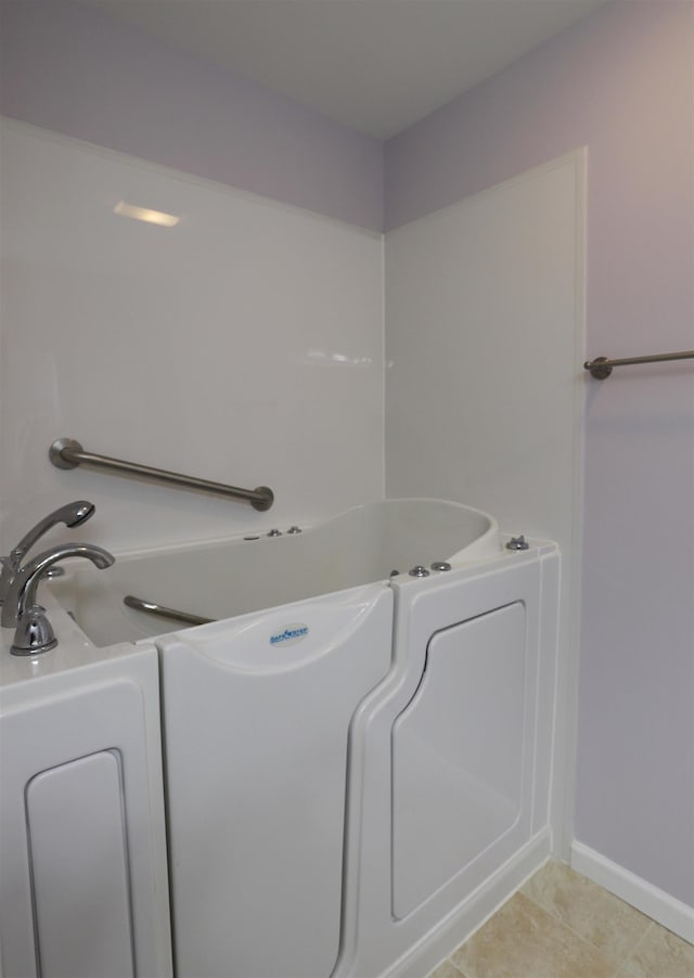 bathroom featuring a tub to relax in, tile patterned flooring, and baseboards