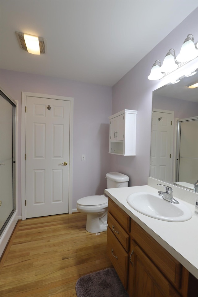 full bathroom featuring toilet, a shower stall, wood finished floors, and vanity