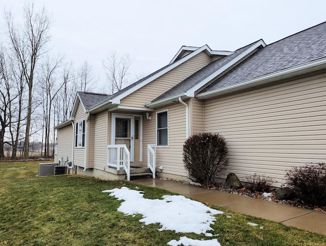 view of front facade featuring roof with shingles and a front yard