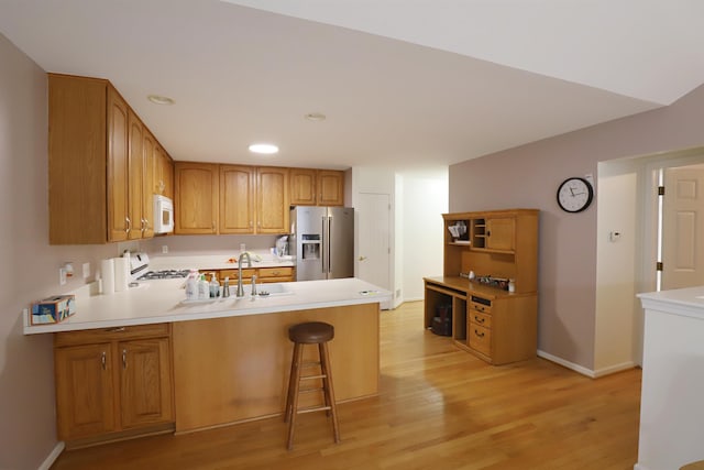 kitchen featuring stainless steel fridge with ice dispenser, white microwave, a peninsula, a sink, and gas stove