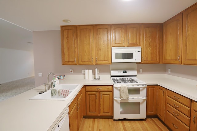 kitchen featuring brown cabinetry, white appliances, light countertops, and a sink