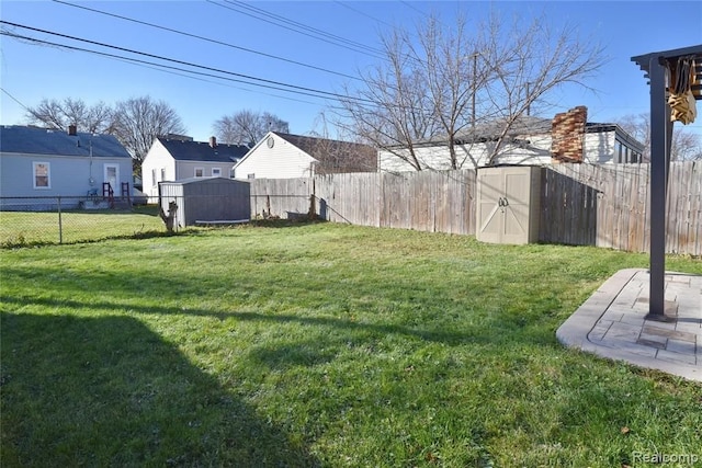 view of yard featuring a fenced backyard, a storage unit, and an outdoor structure