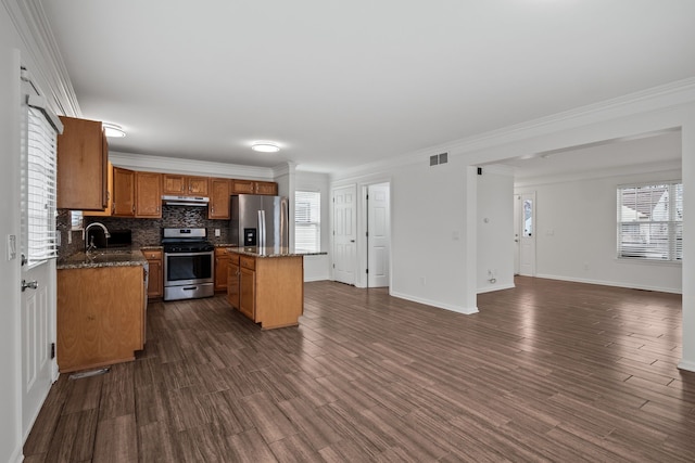 kitchen with dark wood-style floors, a center island, stainless steel appliances, tasteful backsplash, and a sink