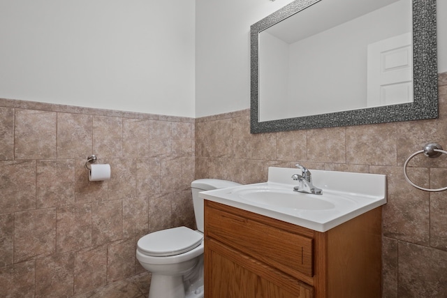 bathroom with tile walls, wainscoting, vanity, and toilet