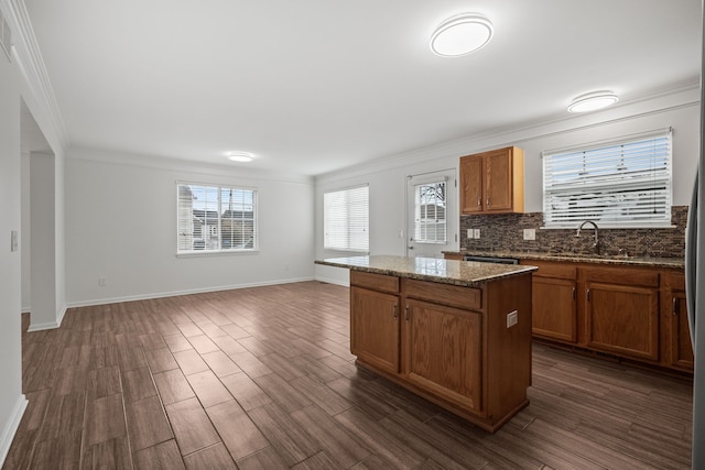 kitchen featuring tasteful backsplash, a center island, dark wood-style flooring, and ornamental molding