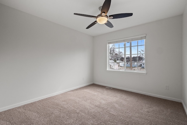 carpeted spare room with a ceiling fan, visible vents, and baseboards