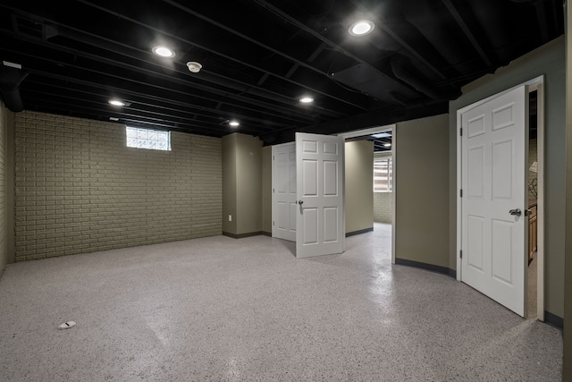 basement featuring baseboards and brick wall