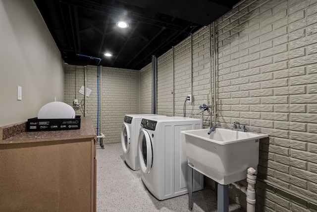 laundry area with brick wall, laundry area, and washing machine and dryer