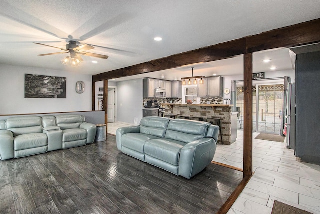 living area with ceiling fan, wood finished floors, a textured ceiling, beam ceiling, and recessed lighting