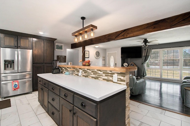 kitchen featuring open floor plan, marble finish floor, light countertops, stainless steel fridge, and decorative light fixtures