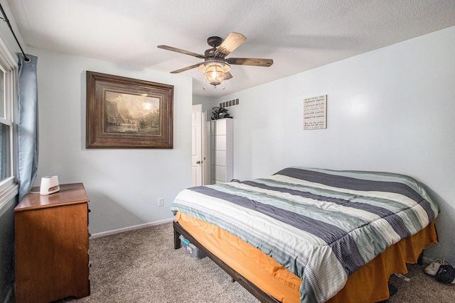 carpeted bedroom with a ceiling fan, visible vents, a textured ceiling, and baseboards