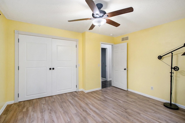 unfurnished bedroom featuring light wood finished floors, a closet, visible vents, ceiling fan, and baseboards