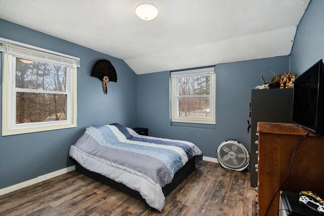 bedroom with vaulted ceiling, a textured ceiling, baseboards, and wood finished floors