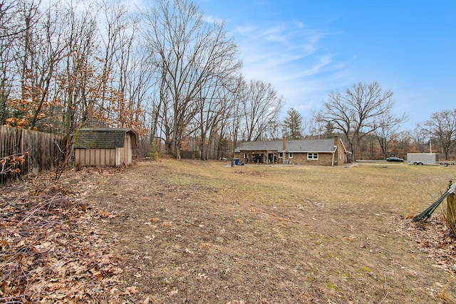 view of yard featuring an outbuilding, a storage unit, and fence